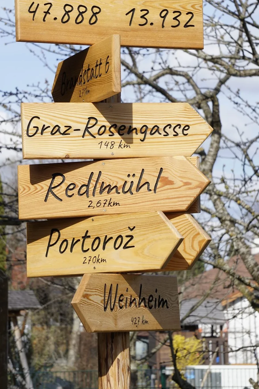 Hoher Holzwegweiser mit mehreren Richtungsschildern und Ortsnamen